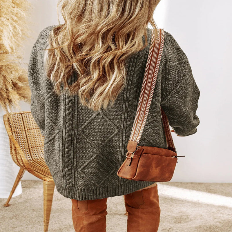 Person wearing a green cable knit sweater with a brown leather bag. - Fashlot