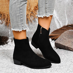 Black ankle boots worn with light gray jeans on a textured surface. - Fashlot
