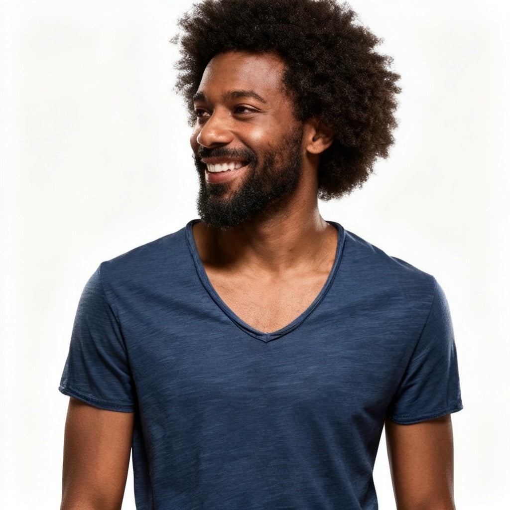 A smiling man with an afro hairstyle and beard wearing a heathered navy blue v-neck t-shirt, photographed against a clean white background. - Fashlot