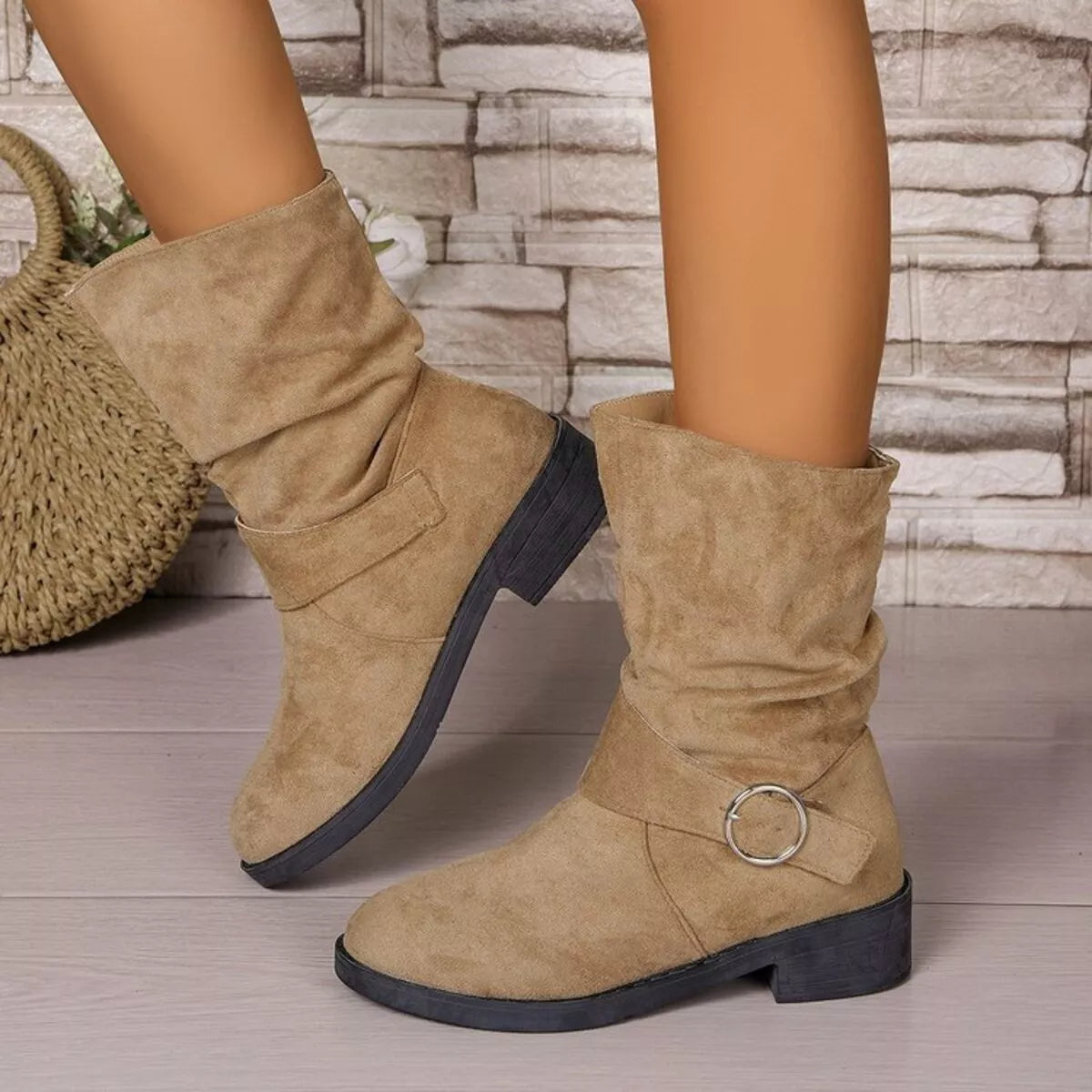Beige boots with a buckle detail worn by a person, against a stone wall background. - Fashlot 