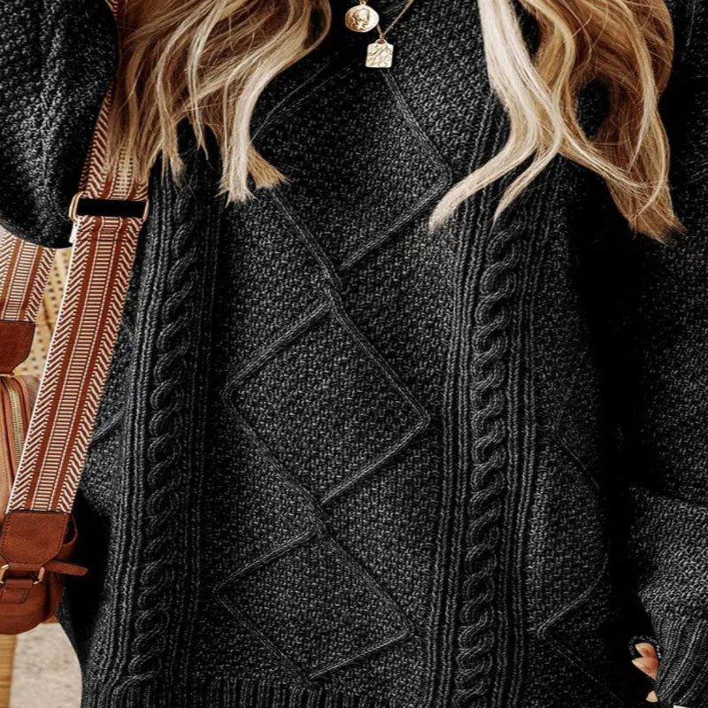Person wearing a dark gray cable knit sweater with a patterned bag in the background - Fashlot