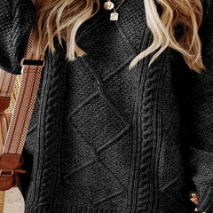 Person wearing a dark gray cable knit sweater with a patterned bag in the background - Fashlot