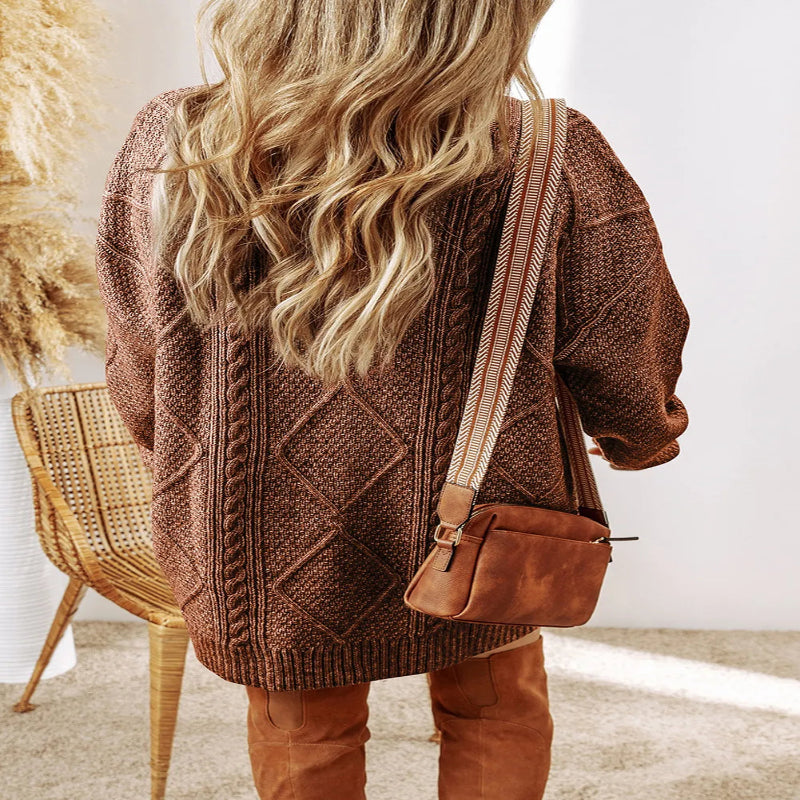 Person wearing a brown knitted cardigan and holding a brown bag indoors. - Fashlot