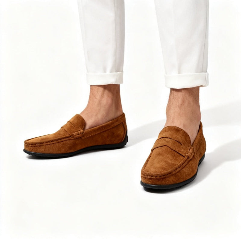 A person wearing cuffed white trousers and tan suede penny loafers with black soles, shown from the calves down against a clean white studio background. - Fashlot