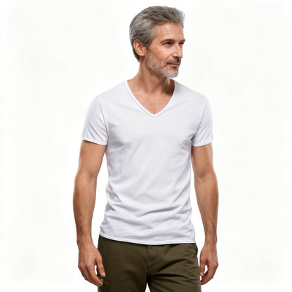 A man with gray hair and a beard wearing a plain white v-neck t-shirt and olive green pants, standing against a solid white background. - Fashlot