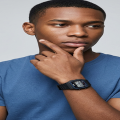 A man wearing a black digital Casio watch on his wrist, posing in a blue t-shirt against a light gray background. - Fashlot