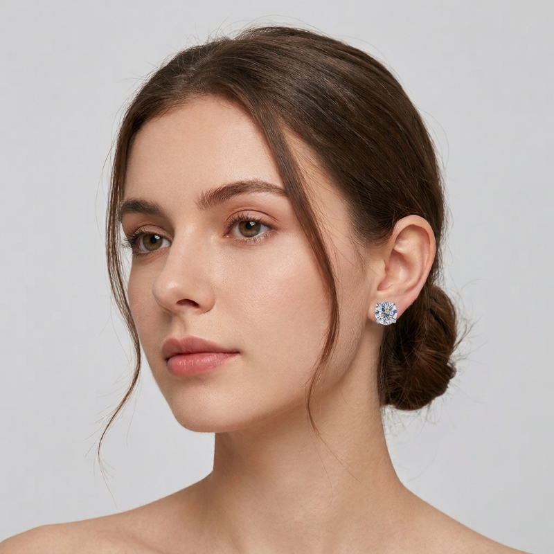 A close-up portrait of a woman with her hair pulled back, wearing a small round stud earring with a clear faceted gemstone in a silver-toned setting against a light gray background. - Fashlot