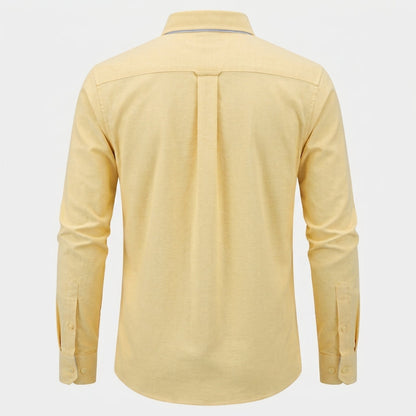 A pale yellow long-sleeve button-up shirt shown from the back, featuring a central pleat and button cuffs, displayed on a light gray background. - Fashlot