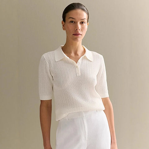 Woman wearing a off white knit top and white pants against a beige background - Fashlot