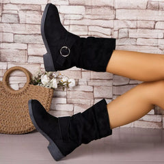 Black knee-high boots worn by a person with a woven bag and flowers on a stone wall background - Fashlot