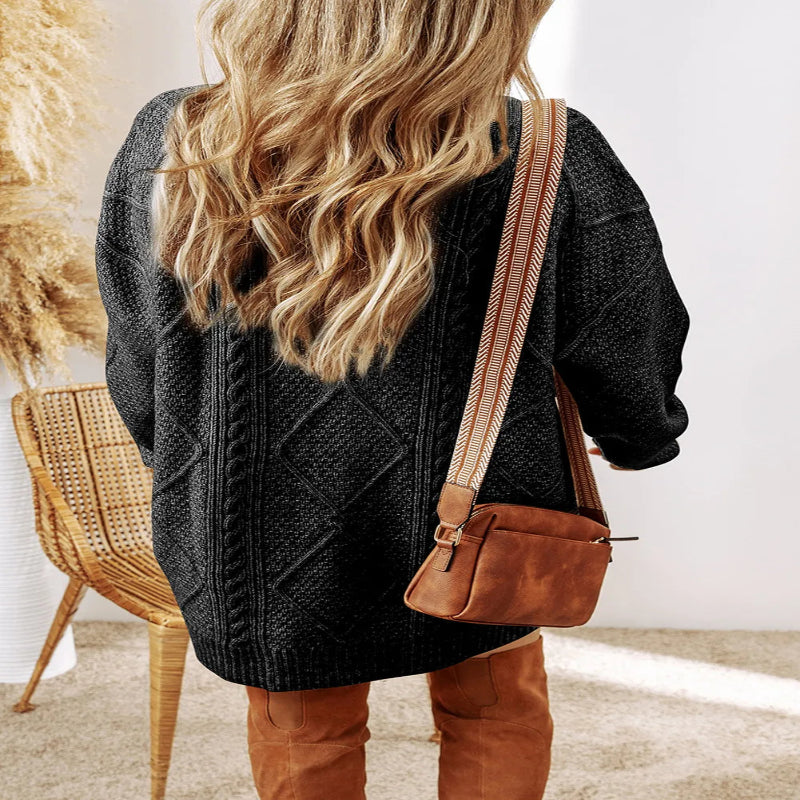 Person wearing a gray sweater and brown leather pants with a brown leather bag, standing indoors. - Fashlot