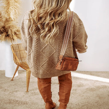 Person wearing a brown cable knit sweater and tan pants, holding a brown leather bag. Fashlot