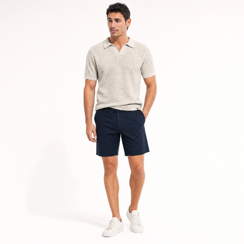A man modeling a aprico short-sleeve polo shirt and dark navy shorts, paired with white sneakers, against a plain white studio background. - Fashlot