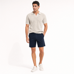 A man modeling a aprico short-sleeve polo shirt and dark navy shorts, paired with white sneakers, against a plain white studio background. - Fashlot