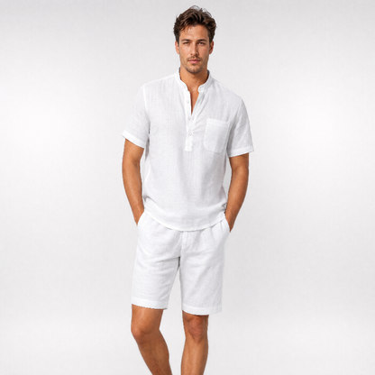 A man modeling a white short-sleeve linen shirt with a half-placket and chest pocket, paired with matching white linen shorts, against a light gray studio background. - Fashlot