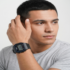 A man wearing a black Casio digital wrist watch with a black strap, shown in a close-up profile shot against a light gray background. - Fashlot